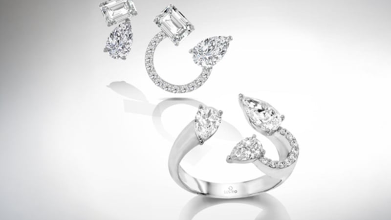 Two pairs of diamond earrings and a diamond ring with marquise and rectangular cuts on a reflective surface, arranged in an artistic layout.